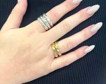 May include: A set of three silver rings and a set of two gold rings. The rings are all textured and have a hammered finish.