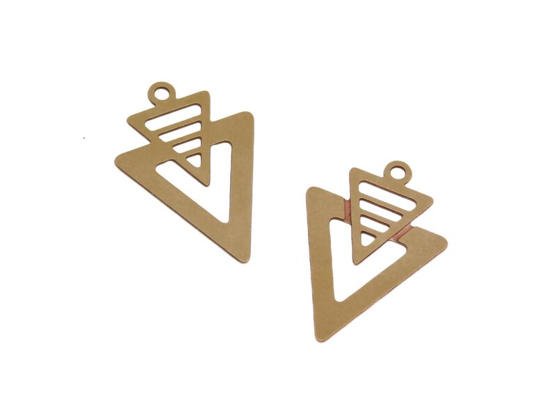May include: Two gold-toned metal triangle charms with a smaller triangle cut out in the center. The charms have a hole at the top for attaching to jewelry.