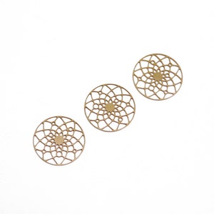 Op de afbeelding: Drie gouden metalen decoratieve cirkels met een delicaat, ingewikkeld, cirkelvormig patroon.
