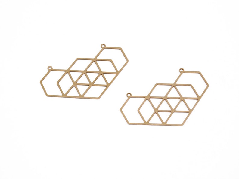 May include: Two gold-toned metal geometric shapes with a hexagonal design. The shapes are open and have a delicate, intricate pattern.