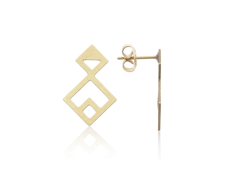 Puede incluir: Un par de pendientes de bot&oacute;n geom&eacute;tricos de oro con un dise&ntilde;o simple y moderno. Los pendientes est&aacute;n hechos de metal fino y tienen una forma cuadrada con un cuadrado m&aacute;s peque&ntilde;o cortado en el centro.