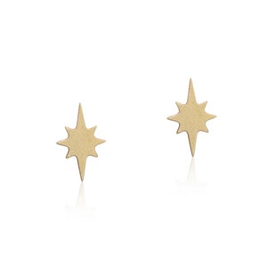 May include: A pair of gold star-shaped earrings. The earrings are small and delicate, and they have a simple, elegant design.