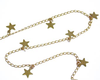 May include: A gold chain necklace with star-shaped charms hanging from it.