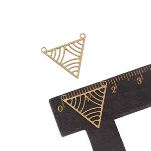 May include: Two gold-colored metal triangle pendant charms with a geometric pattern. The charms are approximately 2 inches in length.