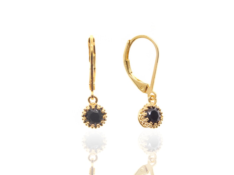 May include: A pair of gold earrings with black gemstone accents. The earrings have a leverback closure.