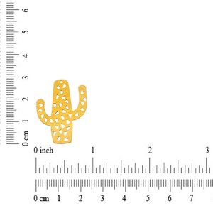 May include: Gold-colored metal cactus cutout with a detailed design. The cactus is approximately 1 inch tall.