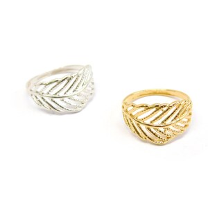 May include: Two leaf-shaped rings, one silver and one gold. The rings are delicate and have a detailed design.