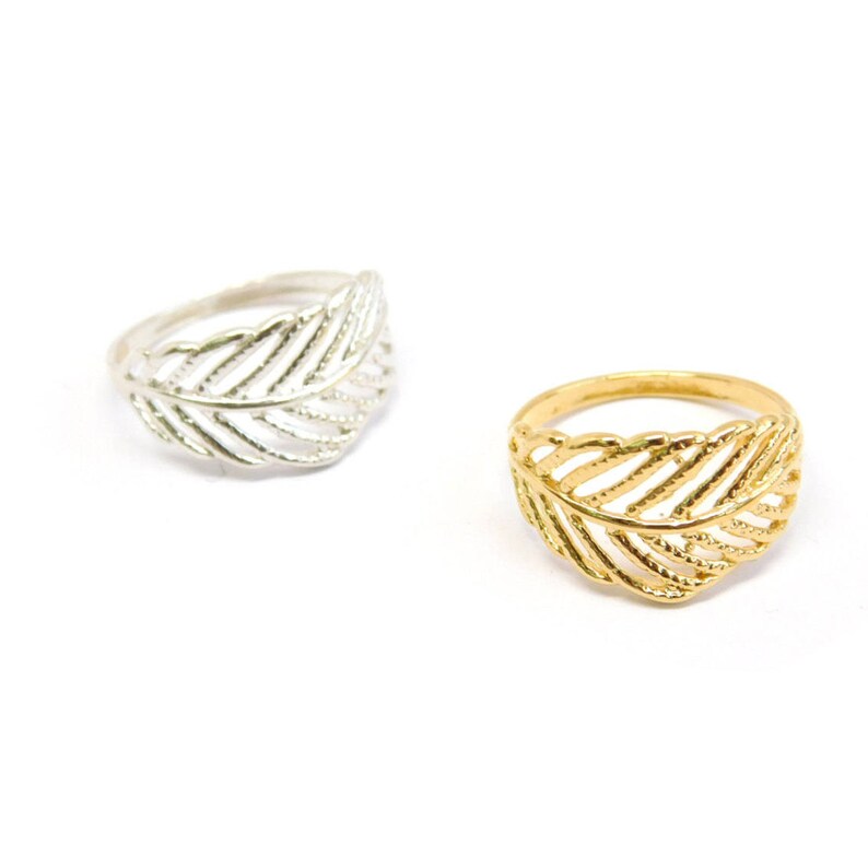 May include: Two leaf-shaped rings, one silver and one gold. The rings are delicate and have a detailed design.