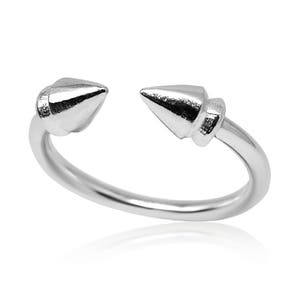 Puede incluir: Un anillo de plata con dos puntas puntiagudas a cada lado. El anillo está abierto y tiene un acabado liso y pulido.
