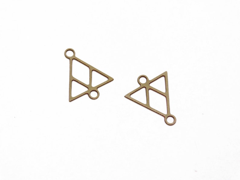 May include: Two gold-toned metal triangle charms with openwork designs and jump rings.