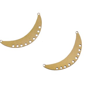 May include: Two gold metal crescent moon shapes with holes around the edges.