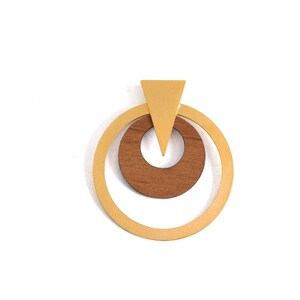 Op de afbeelding: Een geometrische hanger met een lichtbruine houten cirkel in een grotere, lichtgele cirkel. Een lichtgele driehoek bevindt zich boven de cirkels. De hanger is geplaatst tegen een witte achtergrond.