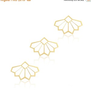 May include: Three gold-colored metal geometric shapes with a starburst design. The shapes are arranged in a triangular pattern.