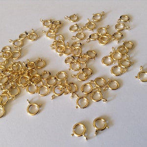 Puede incluir: Un montón de anillos de salto de color dorado, también conocidos como anillos partidos, utilizados para la fabricación de joyas.