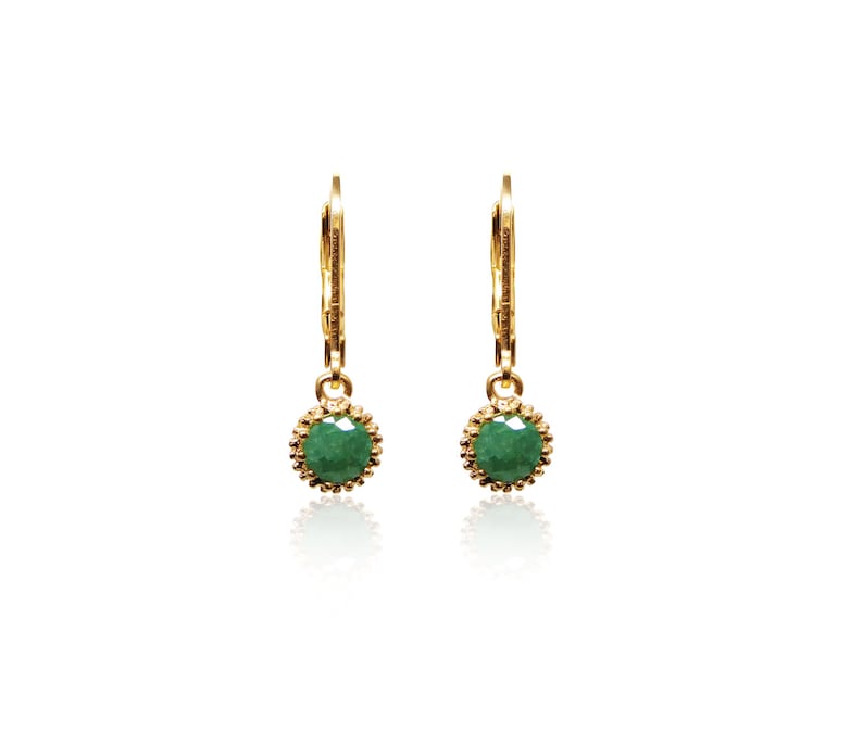 May include: A pair of gold hoop earrings with a green gemstone dangle. The earrings have a delicate, feminine design.