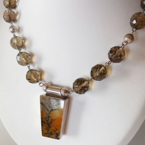 May include: A silver necklace with a brown and orange dendritic agate pendant and faceted brown glass beads.