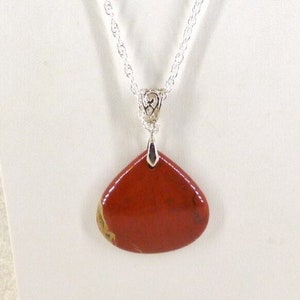 May include: A red gemstone pendant necklace with a silver chain. The pendant is a teardrop shape and has a silver bail.