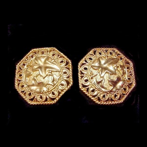 May include: Two gold-colored, octagonal earrings. Each earring features a central design with a star and floral elements, surrounded by a filigree border. The earrings have a vintage or antique aesthetic.