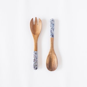 May include: A set of two wooden serving utensils with blue and white patterned handles. The utensils are a spoon and a fork.