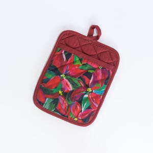 May include: Red quilted pot holder with a floral print of red poinsettia flowers and green leaves.
