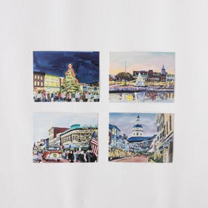 May include: Four illustrated postcards featuring different scenes of a city at night. The first postcard shows a brightly lit Christmas tree in the center of a street with buildings on either side. The second postcard shows a cityscape with a river in the foreground. The third postcard shows a street with a red truck and people walking. The fourth postcard shows a street with a large building in the background.
