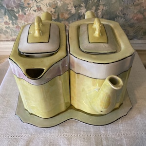 May include: A yellow and white porcelain teapot set with a matching creamer and sugar bowl. The set has a geometric design with gold accents.