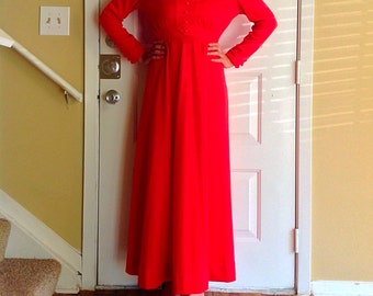 May include: A long, red maxi dress with a button-up front and long sleeves. The dress has a fitted bodice and a flowing skirt.