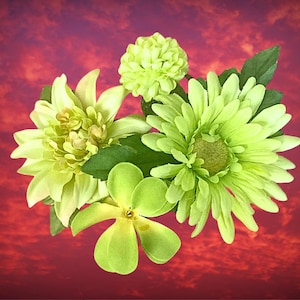 May include: A cluster of artificial flowers in shades of green and yellow, including dahlias and daisies, with green leaves. The flowers are set against a vibrant red and purple background.