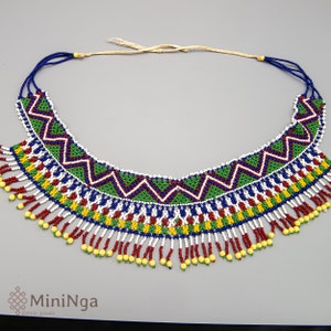 May include: A colourful beaded necklace with a geometric pattern and fringe. The necklace is made with blue, green, red, white, and yellow beads.