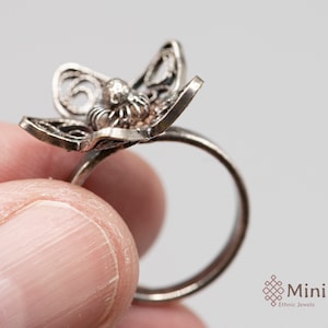 May include: Silver filigree ring with a delicate butterfly design. The ring is open and has a simple band.