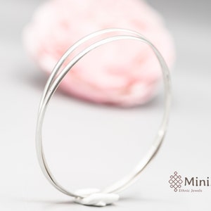 Può includere: Un braccialetto rigido in argento a doppia fascia. Il braccialetto è semplice ed elegante, con una finitura liscia.