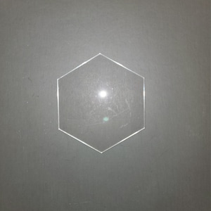 May include: A clear hexagon-shaped acrylic blank for crafting projects.