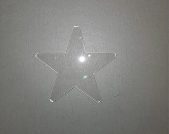 May include: A clear plastic star-shaped cutout on a gray background.
