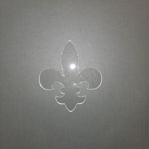 May include: A clear plastic fleur-de-lis cutout.