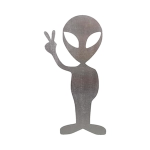 May include: A silver-colored alien figurine with large eyes and a peace sign gesture. The figurine is made of metal and has a textured surface.