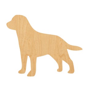 May include: A flat, two-dimensional wooden cutout in the shape of a standing dog. The object features a light tan, natural wood grain texture with a smooth finish, depicting the silhouette of a canine in a side profile view facing to the left.