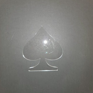 May include: A clear plastic stencil of a spade playing card suit.