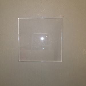 May include: A clear square piece of acrylic plastic, possibly a sheet protector or a display case.