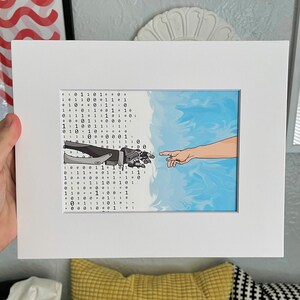 May include: White framed art print depicting a robotic hand reaching towards a human hand, set against a binary code and a blue, cloud-like background. The artwork is a modern interpretation of the Creation of Adam.