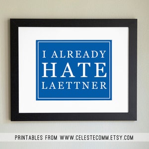 Peut inclure: Impression encadrée avec un fond blanc et un carré bleu contenant le texte "I ALREADY HATE LAETTNER" en blanc. Le cadre est noir et l'impression comprend le texte "PRINTABLES FROM WWW.CELESTECOMM.ETSY.COM" en bas.