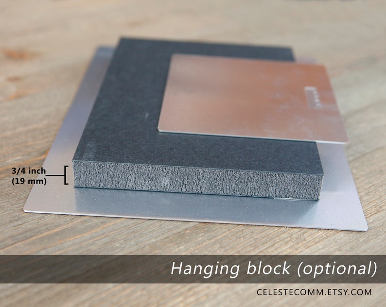 May include: A close-up of a metal print with a hanging block attached to the back. The hanging block is 3/4 inch (19 mm) thick. The metal print is on a wooden surface.