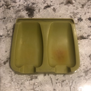 May include: A green plastic dish rack with two slots for holding utensils. The dish rack is labeled "Tupperware".