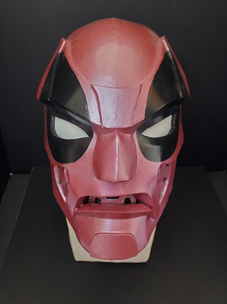 Pu&ograve; includere: Una maschera rossa e nera con aperture bianche per gli occhi. La maschera ha un'espressione severa ed &egrave; probabilmente un costume o un accessorio. La maschera &egrave; realizzata in un materiale solido e ha una finitura liscia.