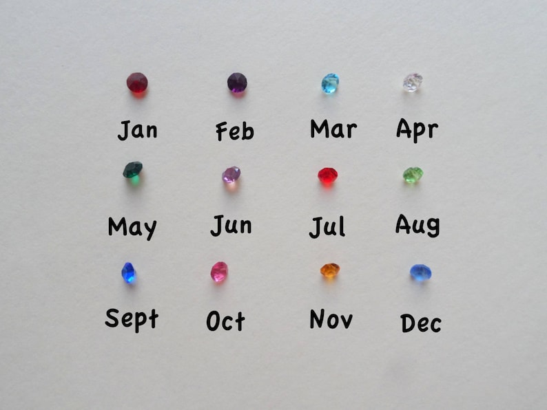 May include: A chart with twelve colored gemstones representing the months of the year. January is red, February is purple, March is blue, April is clear, May is green, June is pink, July is red, August is green, September is blue, October is pink, November is orange, and December is blue.