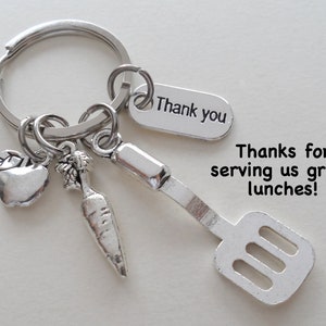 May include: Silver keychain with a spatula, apple, carrot, and a tag that says "Thank you". The text "Thanks for serving us great lunches!" is also visible.