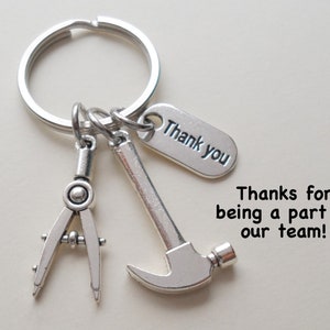 May include: Silver-toned keychain with a compass, hammer, and a tag that says "Thank you." The text "Thanks for being a part of our team!" is also visible. This keychain is a thoughtful gift for construction workers or anyone in a trade.