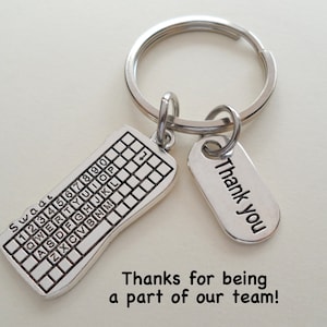 May include: Silver keychain with a keyboard charm and a tag that says "Thank You". The tag is attached to a silver key ring. The text "Thanks for being a part of our team!" is printed below the keychain.