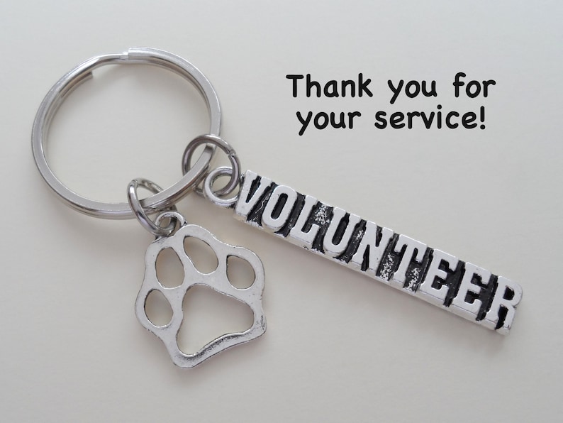 May include: Silver key chain with a paw print charm and a tag that says "VOLUNTEER". The text "Thank you for your service!" is written above the keychain.