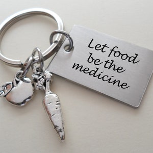 May include: Silver keychain with a rectangular tag that reads "Let food be the medicine". The keychain also has a small apple and carrot charm.