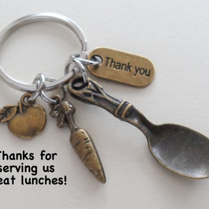 May include: A silver key chain with a small spoon, apple, and carrot charm. The tag says "Thank you".